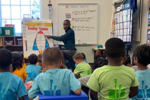 Teacher pointing at post-it note board while instructing students