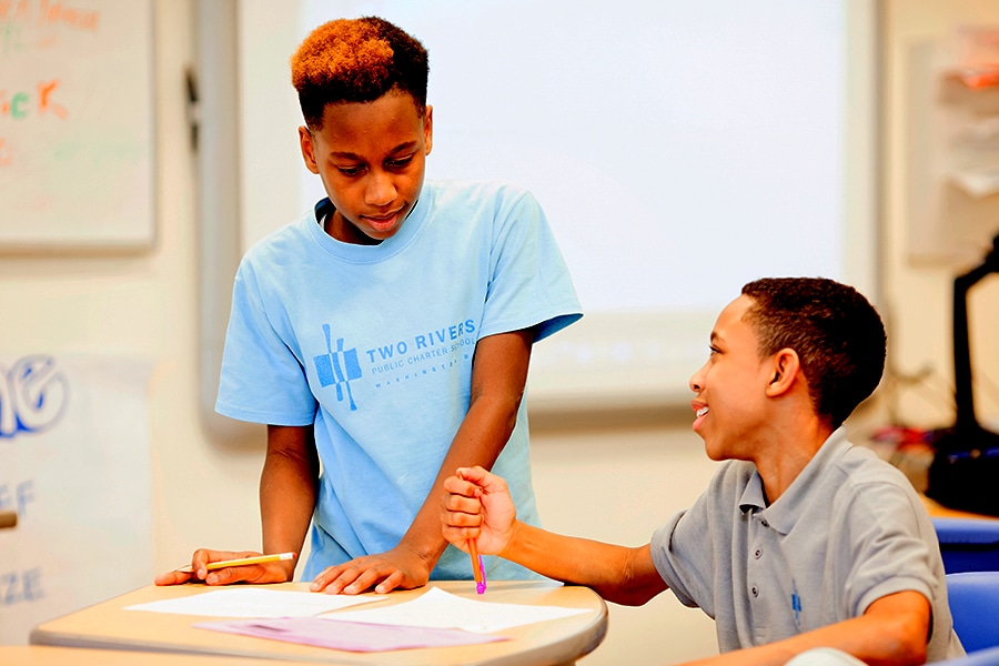 Two students talking while working at table